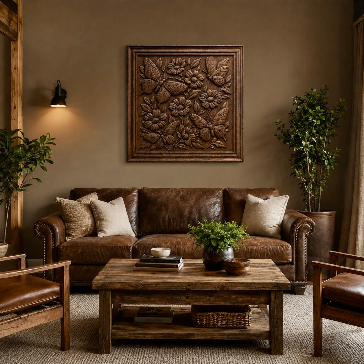 A cozy living room features a brown leather sofa, two matching chairs, a wooden coffee table, and potted plants. Above the sofa, the Butterflies and Flowers CNC Relief STL File | Floral CNC Wall Art by Form Arcade adds artistic flair. Neutral tones throughout the space create a warm, inviting atmosphere—perfect for highlighting unique woodworking projects.